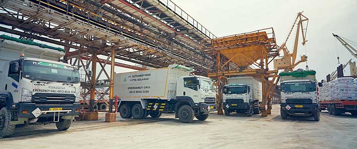 Proses distribusi barang industri melalui pergudangan, penanganan muatan, dan pengangkutan menggunakan truk.