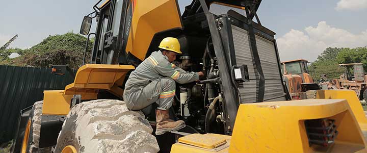 Teknisi memeriksa kondisi mesin excavator untuk perawatan alat berat